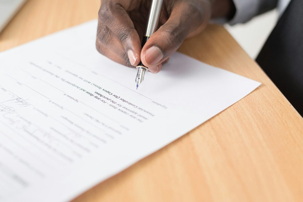 A person filling out a court record form by hand while seated at a desk